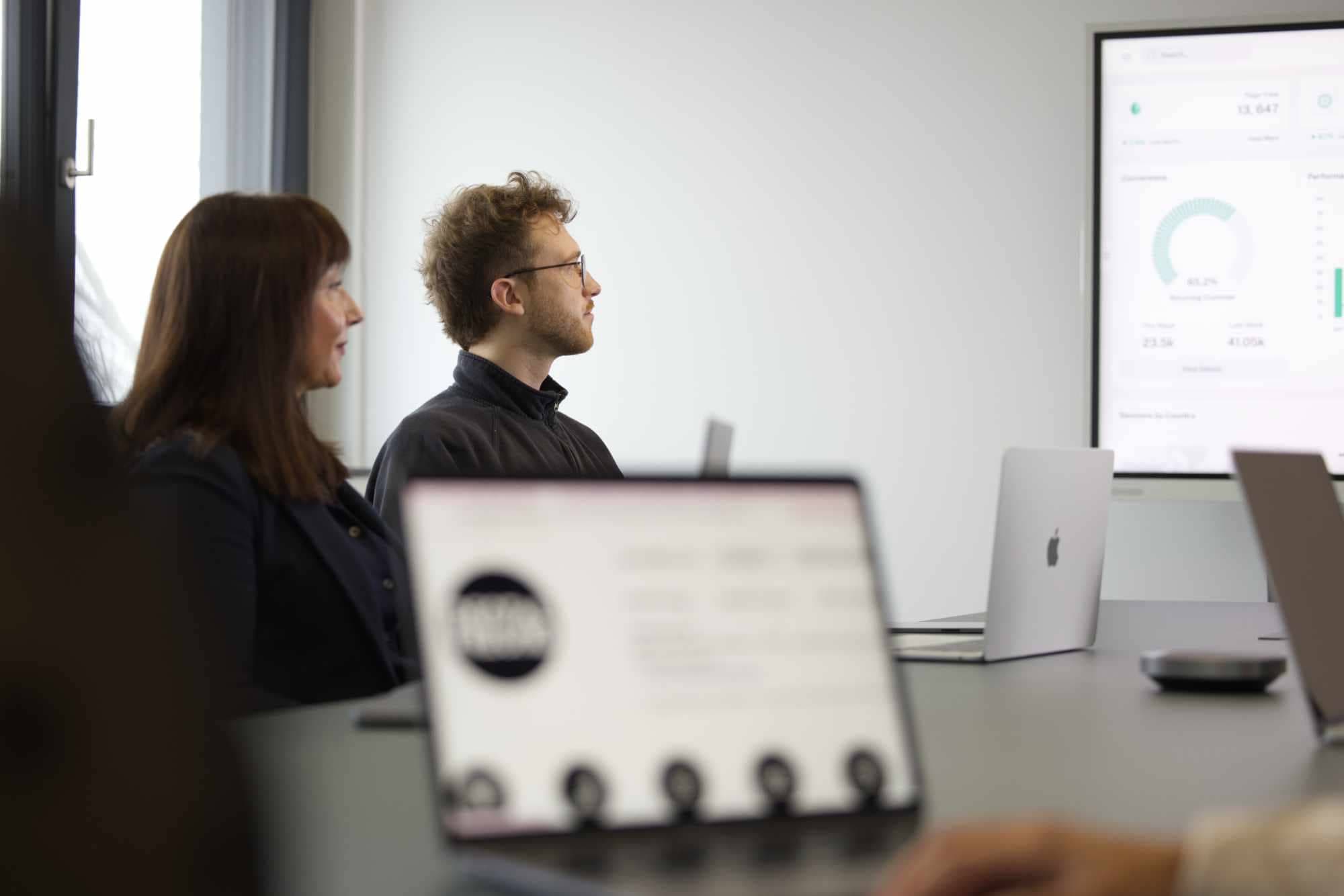 DENTALFREUND Teammitglieder im Meeting vor einem Dashboard